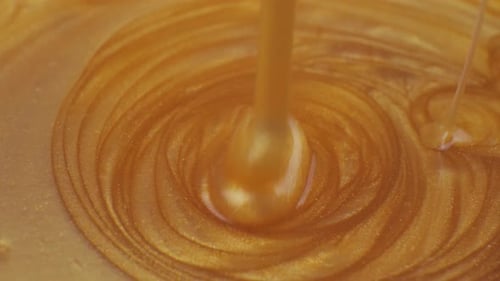 Pouring Golden Liquid Creating Swirls and Patterns