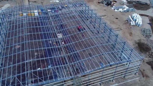 Sitio de construcción de edificio industrial moderno sin terminar, estructura de acero, vista aérea desde arriba, zoom