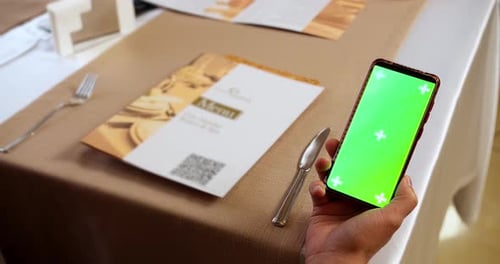 Man holding smartphone in hand with green screen mock up. Hand holding smartphone with green screen