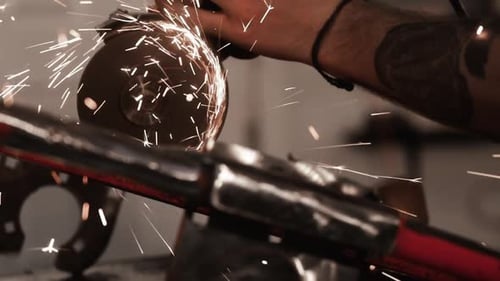 Close shot of a grinding disc with many hot metal sparks coming out. Mechanic working on custom fabr