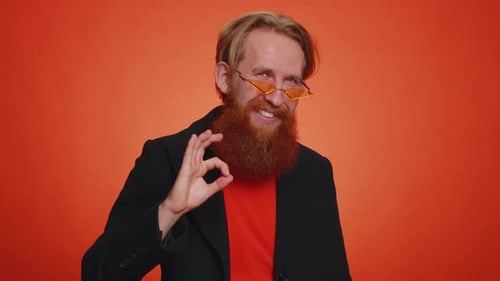 Bearded Man Gives Okay Gesture on Orange Backdrop