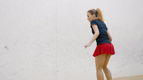 Focused Woman with Ponytail Hits Squash Rubber Ball on Court