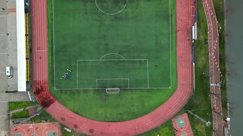 football players gather at an empty football field, drone top-down shot