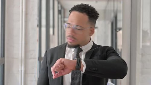Young Adult Businessman Checking Watch in Office Building