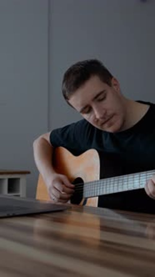 Vertical of Man Learns to Play Guitar and Sings Watching Online Lesson