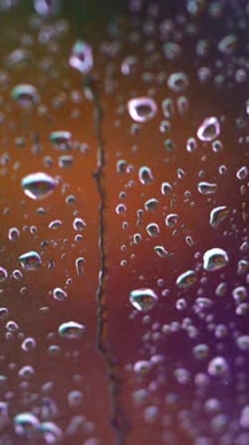 Droplets on colorful background. Raindrops flow down the glass window.