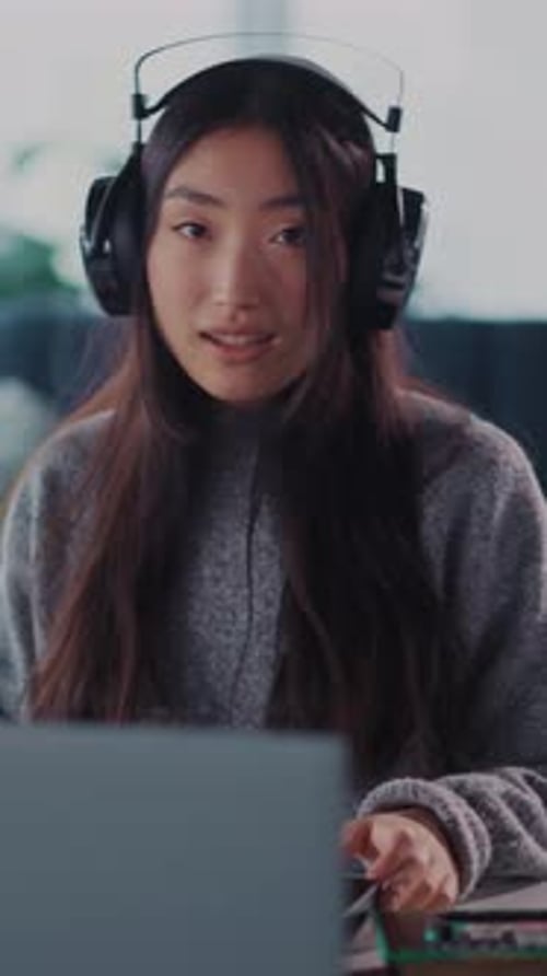 Smiling Young Woman Working on Laptop with Headphones
