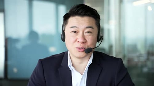 Webcam view. Confident asian businessman in headset talking on a video call looking at camera