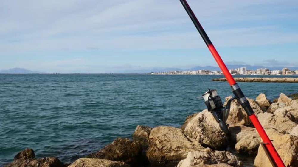 Fishing rod on rocks by blue ocean water, Industrial Stock Footage ft ...