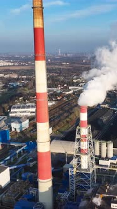 Industrial landscape with smokestacks releasing steam near urban area