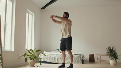 Young Adult Man Stretching in Bedroom