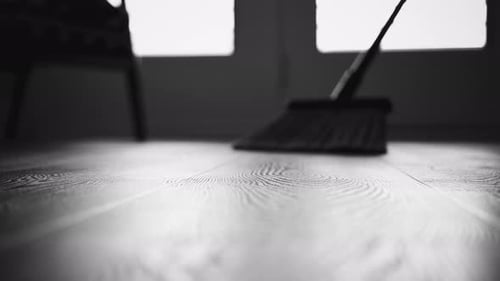 Broom Sweeping Wood Floor in a Monochrome Interior