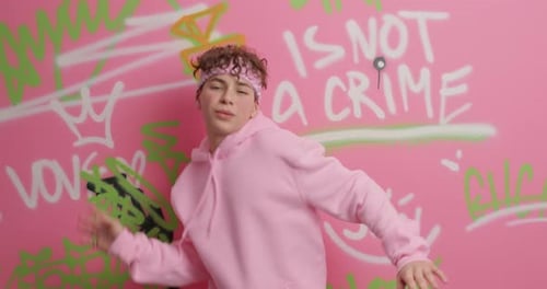 Teen in Pink Hoodie Dancing in Front of Graffiti