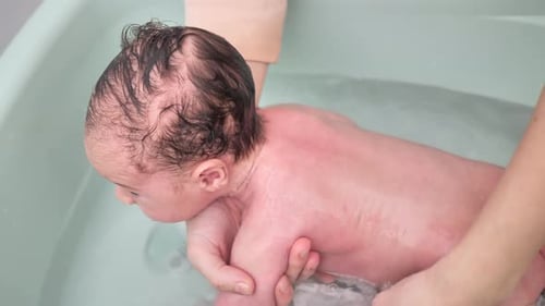 Parent Washing Baby's Hair in Bathtub Close Up
