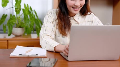Close-up, beautiful Asian office worker, sitting working on laptop computer placed on table in front