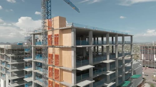 Rotierende Luftaufnahmen eines im Bau befindlichen Hotels mit Stadt im Hintergrund, Drohnenaufnahme