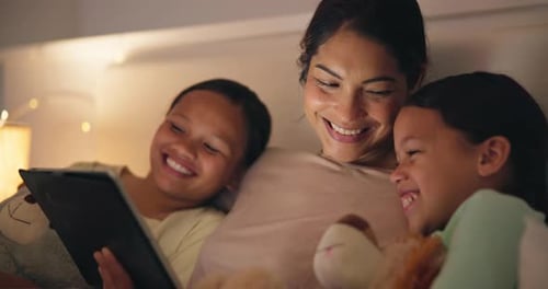 Mother and Daughters Enjoying Tablet Time in Bed