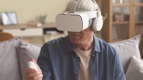 Homem de cabelos grisalhos jogando jogos VR em ambientes fechados