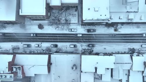 Luftaufnahme der Stadtstraße von oben nach unten während eines Schneesturms. Schneegestöber fliegen über Gebäude
und Karussell