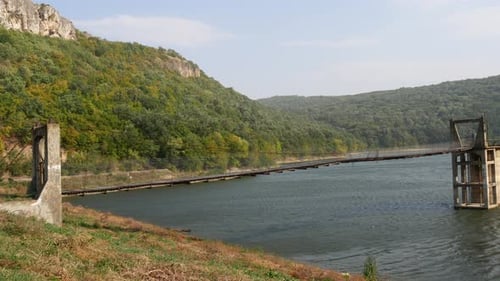 Hängebrücke mit Holzdeck über den Gebirgsfluss.