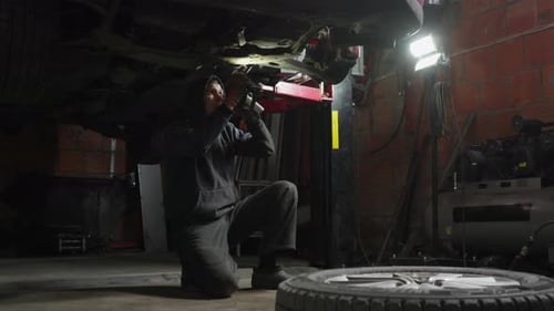 Professional auto mechanic working on car suspension at a repair service shop