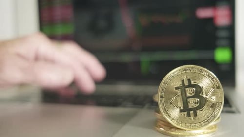 bitcoin golden coin with laptop and stock market chart in background caucasian hand trading online ,