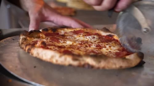 Slicing a Freshly Made Pepperoni Pizza