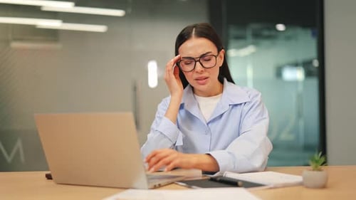 Woman Experiencing Headache While Using Laptop in Office