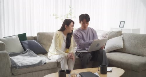 Couple Using Laptop Together on Couch Indoors