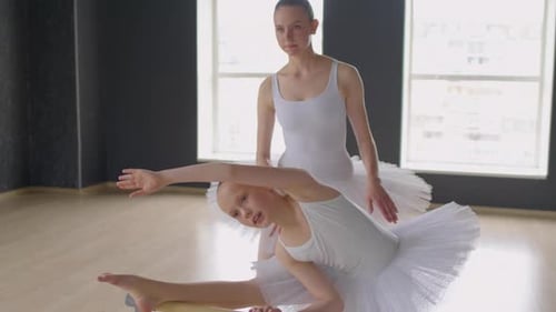 Girl in Tutu Pulling Body to Her Leg with Teacher at Barre
