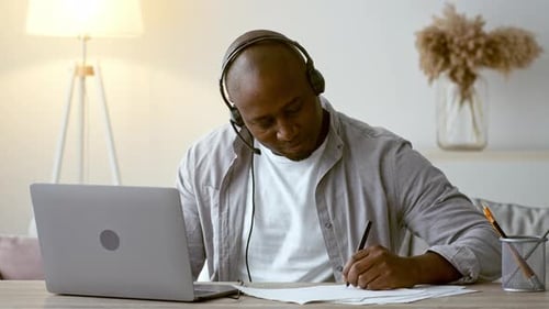Man Wearing Headset Using Laptop at Home