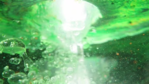 View From Underwater On A Green Surface, Pouring Liquid Inside And Bubbles Dispersing Underwater.