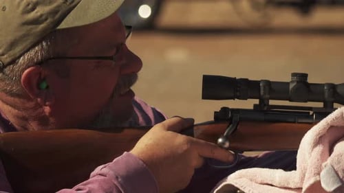 Well-seasoned hunter smiles as he hits the target while sighting his gun right before the fall deer
