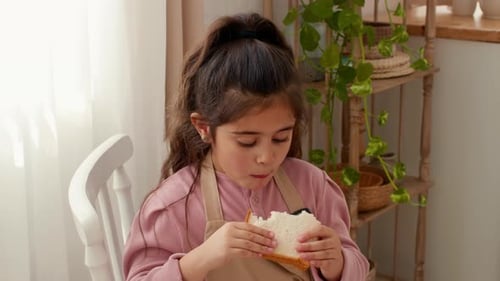 Adorable girl eating a sandwich indoors at home
