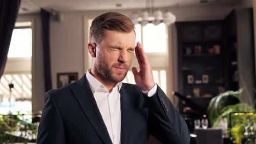Tired Businessman Having Headache Standing in Restaurant