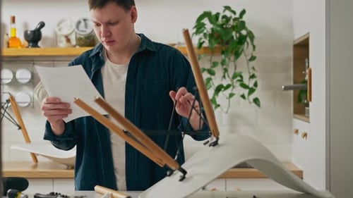 Assemblage, un jeune homme étudiant indépendamment les instructions pour assembler des meubles tout en