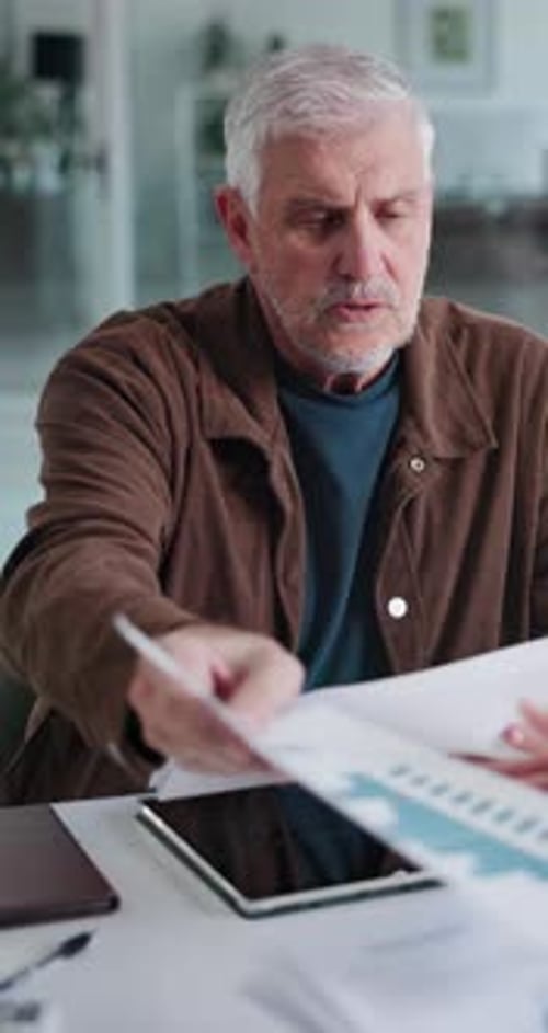 Man Reviews Paperwork at Home on Tablet