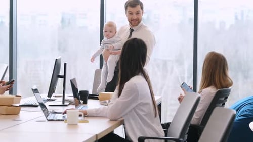 L'homme est debout, parle aux employés et tient un petit garçon dans ses mains. Groupe de personnes travaillant i