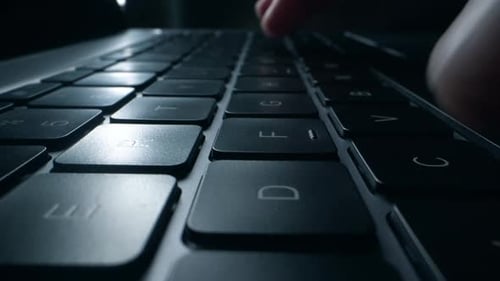 Primer plano de las manos escribiendo y codificando en el teclado del ordenador portátil