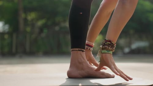 Gros plan d'une femme pratiquant le yoga à l'extérieur au ralenti alors que la lumière du soleil filtre à travers les arbres