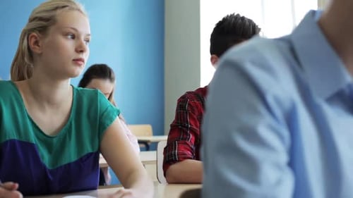 Teenage Students Writing in Classroom at School