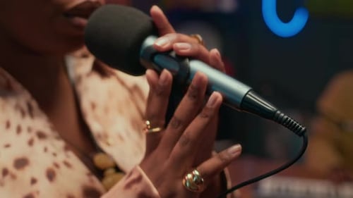 Elegant Woman Singing in Microphone in Vibrant Recording Studio