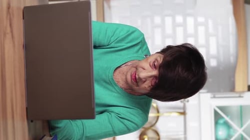 Senior Woman Using Laptop in Bright Kitchen