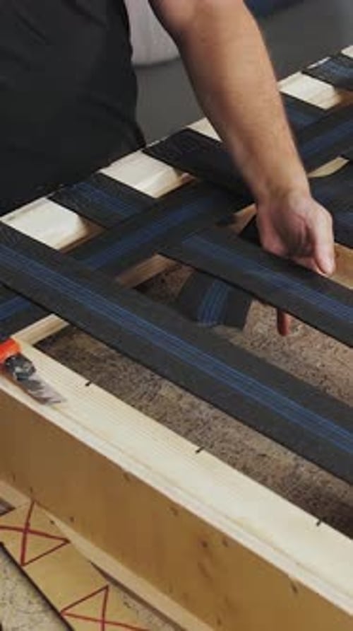 Vídeo vertical de un primer plano de un obrero haciendo un sofá en una fábrica de muebles Manos de un hombre haciendo parte de