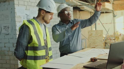 Engineers Reviewing Blueprints at Construction Site