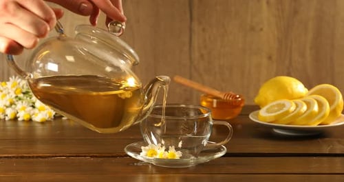 Pouring chamomile tea into a clear glass cup
