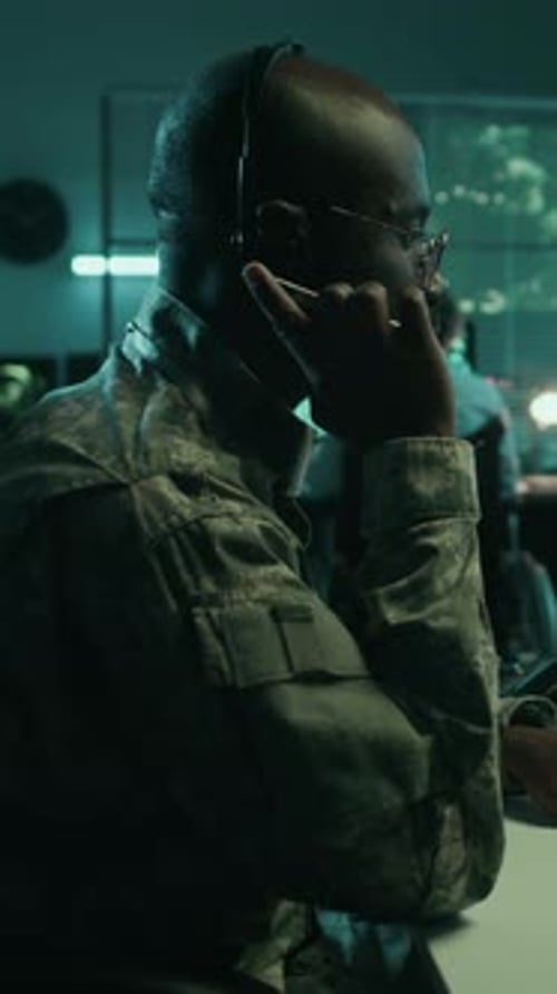 Man in Camouflage Communicating at Desk at Night