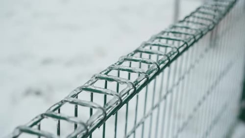 Icy Green Fence with Hanging Icicles in Snowy Winter Park Scene