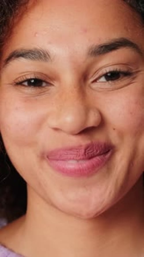 Portrait d'une jeune femme souriante regardant la caméra sur fond lilas en studio
