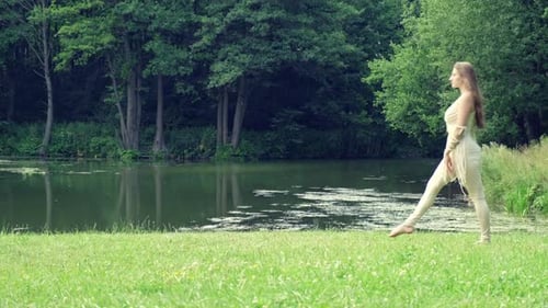 A Beautiful Graceful Girl is Dancing on the Background of the Lake and Forest